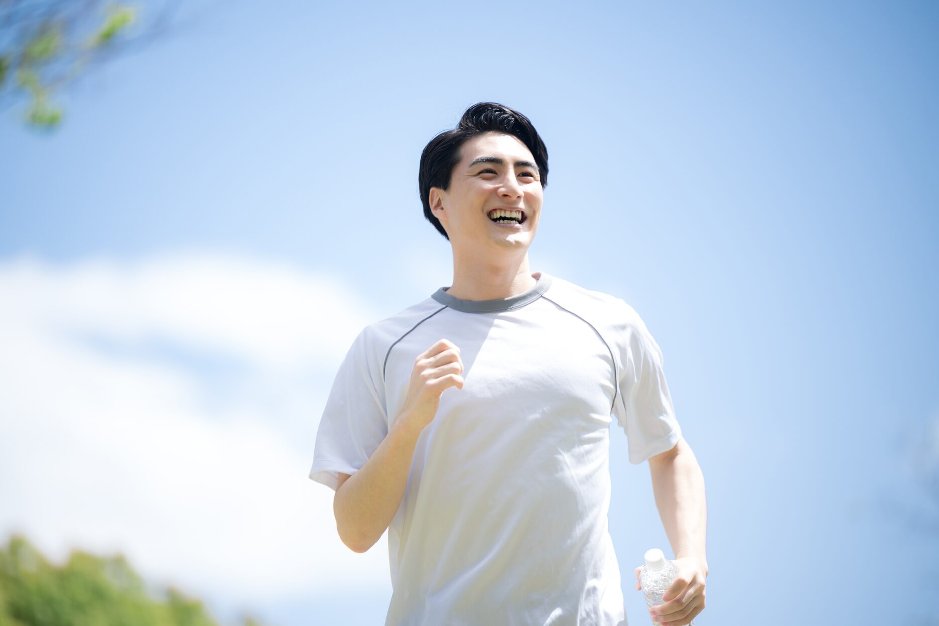青空の下を笑顔で走る男性