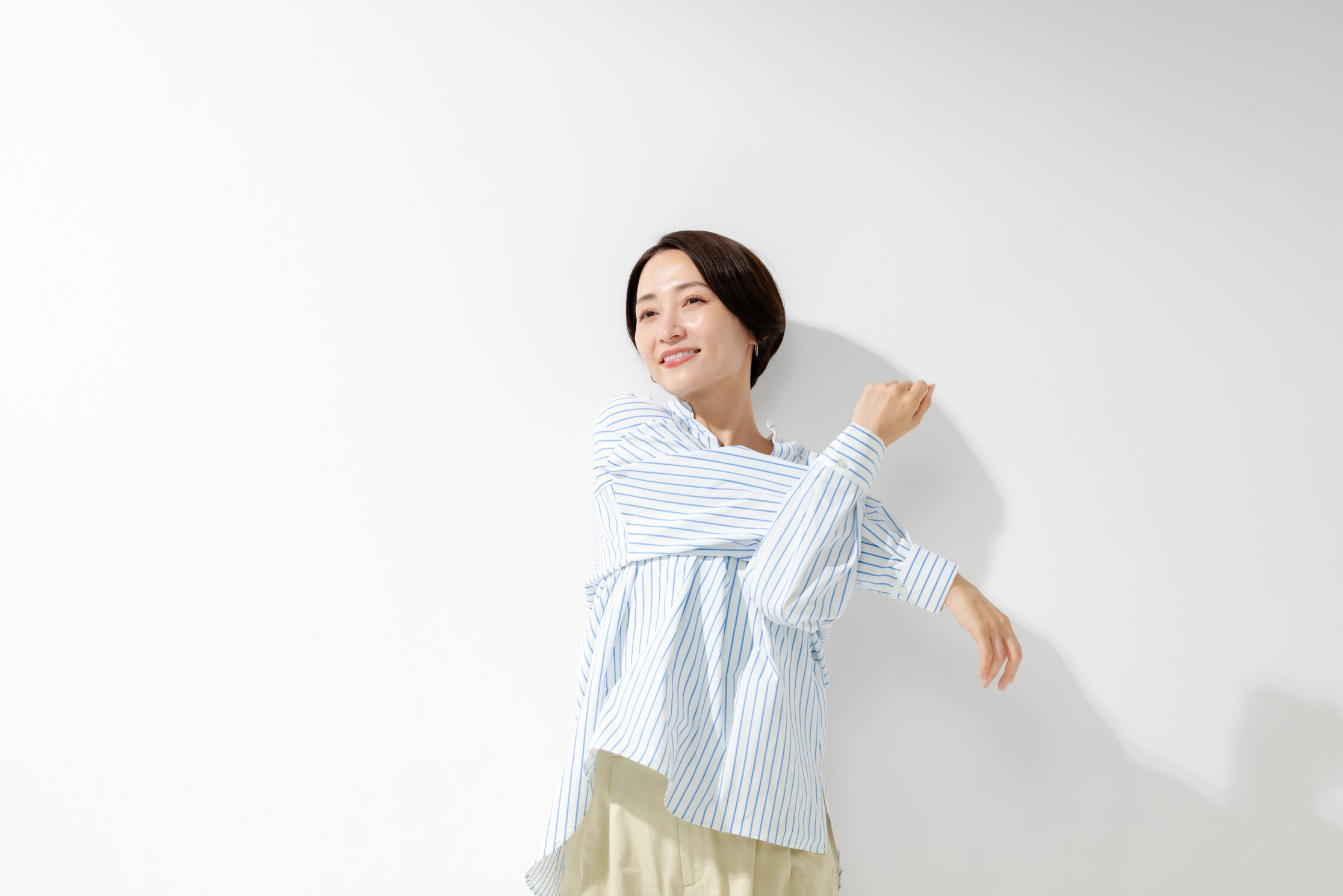 明るい部屋で両手を広げて笑顔を見せる女性